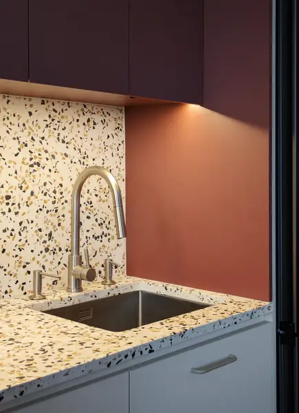Detal zlewu z blatem terrazzo i mosięzną baterią